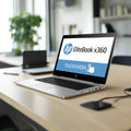 A certified refurbished HP EliteBook x360 1030 G2 13.3" touchscreen laptop (i5-7300U, 8GB RAM, 256GB SSD, Win 10 Pro) sits open on a wooden desk in a modern office, displaying "TOUCHSCREEN," with shelves and another laptop behind it.
