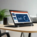 A Lenovo ThinkPad X1 Yoga i5 6300U 2.4GHz 8GB 256GB SSD Touch 14 W10P sits open on a light-colored desk, displaying charts and graphs, with a blurred green plant and a cup visible in the background.